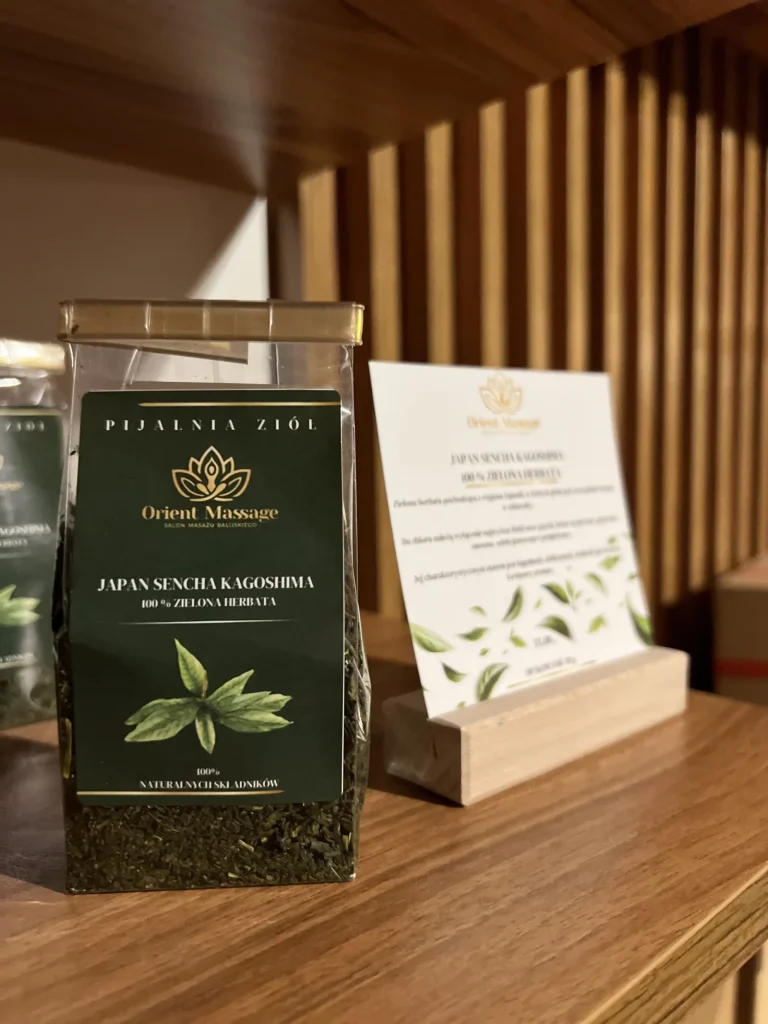 Opakowanie zielonej herbaty obok karty produktu na drewnianej półce.