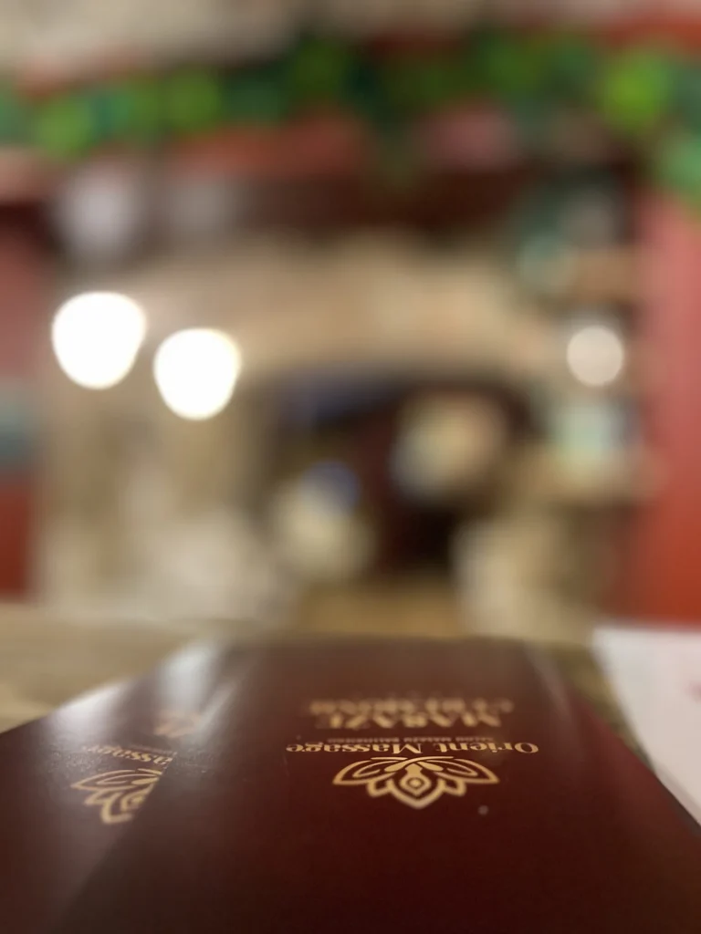 Zbliżenie na bordową okładkę cennika z logo Orient Massage.