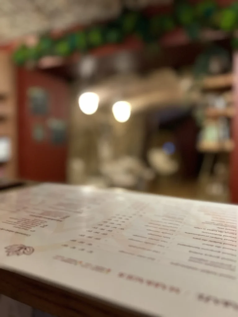 Cennik masaży na ladzie, z wnętrzem salonu w tle.